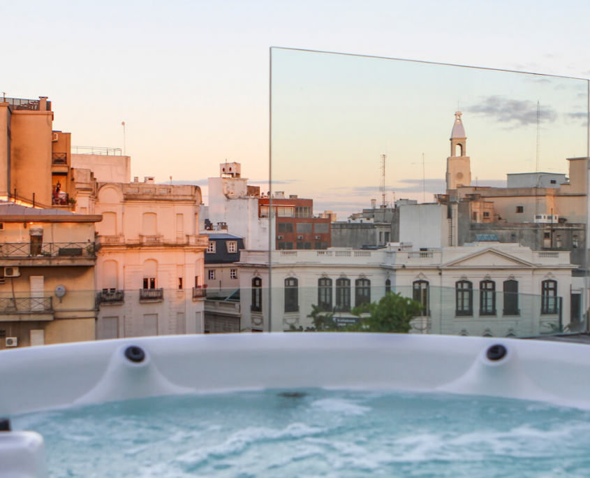 A rooftop jacuzzi at sunset with views over the nearby town