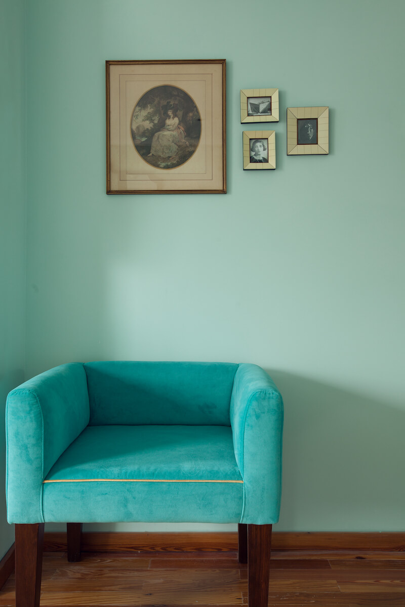 A turquoise velvet armchair with gold details set within the Susanna Soca superior room