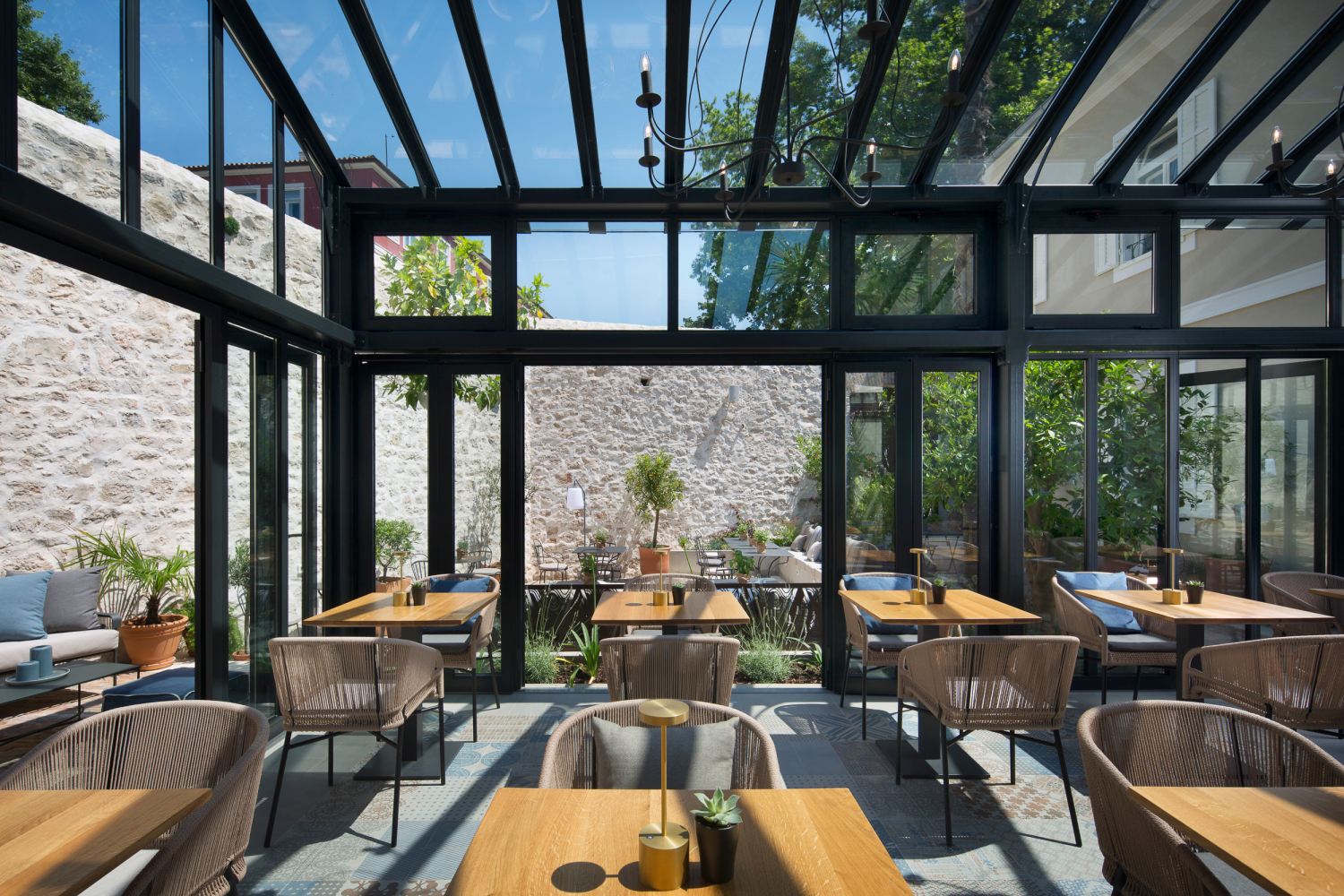 A steel and glass orangery full of wooden dining tables and chairs